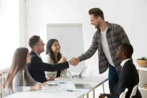 A group of professionals shaking hands during a meeting, representing collaboration among insurance brokers in India.jpg